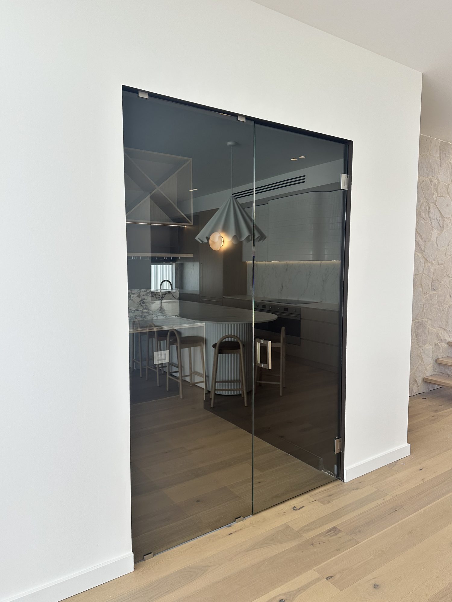 Full-height clear glass wine room — frameless door and fixed panel beside a stone feature wall, Adelaide